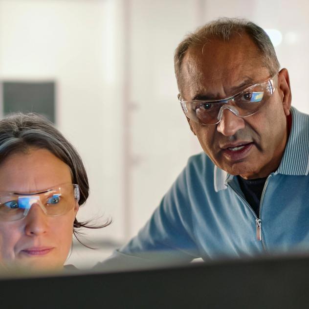 Man and woman wearing safety glasses looking at a monitor