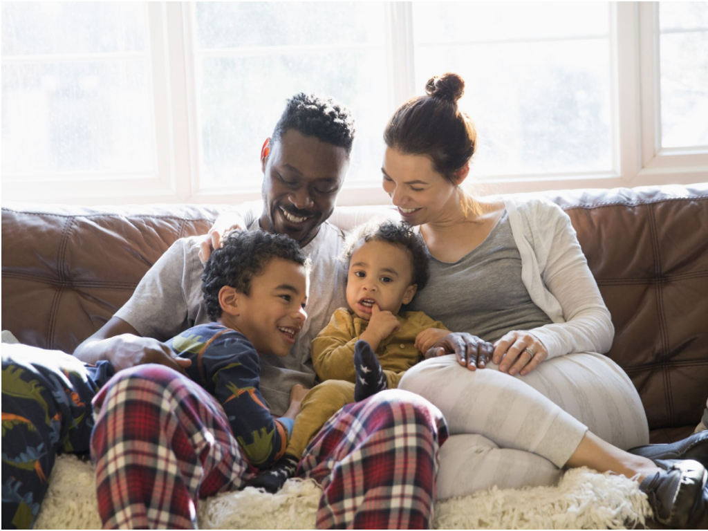 A mixed race family sitting on a couch with young children