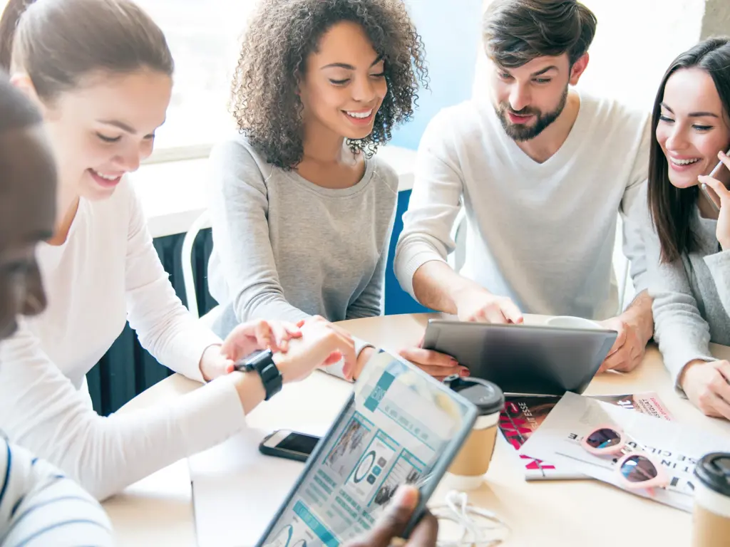 A diverse group of young professionals collaborate on tablets