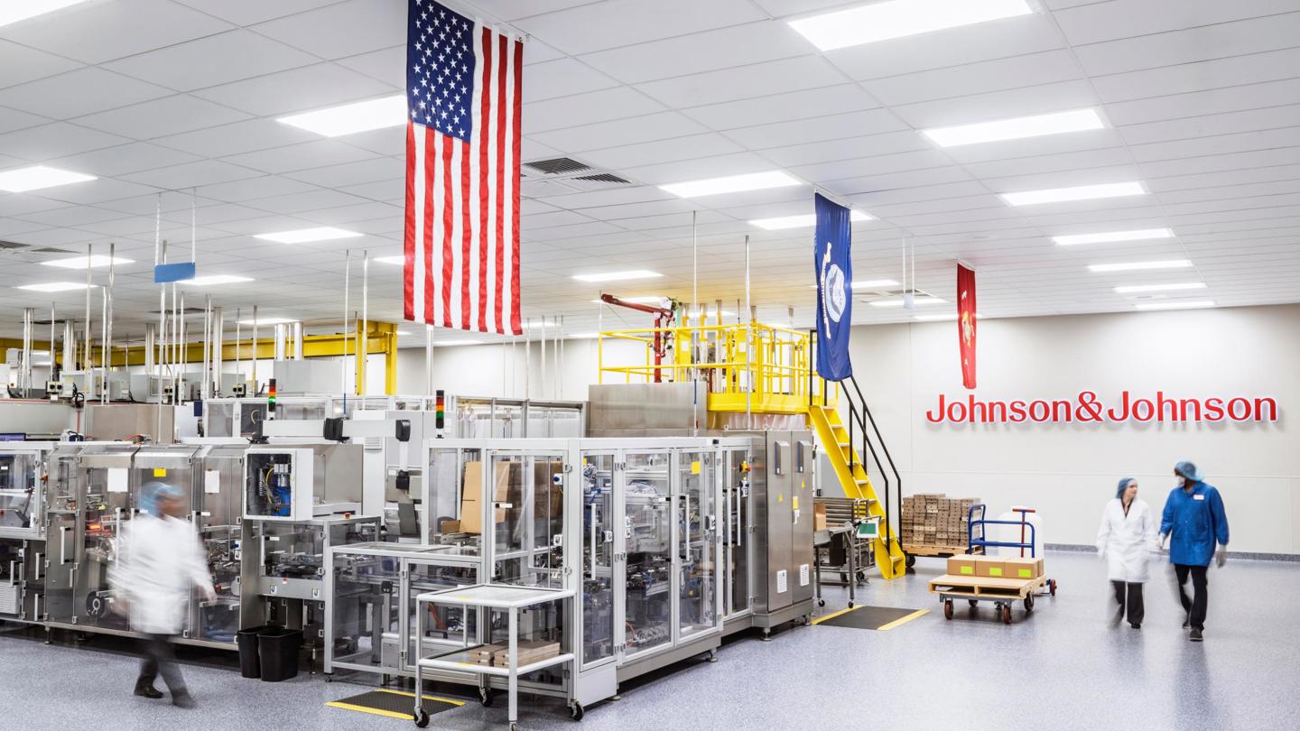 People walking in a J&J biomanufacturing facility with several flags hanging