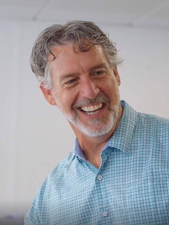 Upper torso portrait of a man smiling wearing a short sleeve blue button down shirt