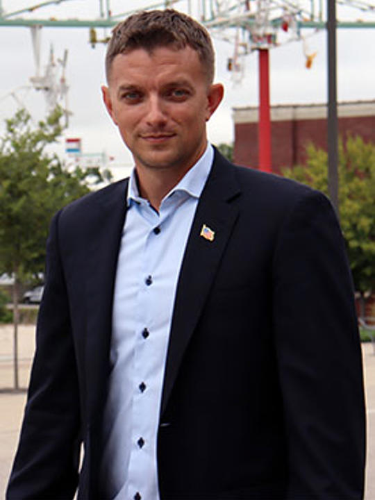 Upper torso portrait of Pete, a man wearing a black suit jacket and blue button down shirt