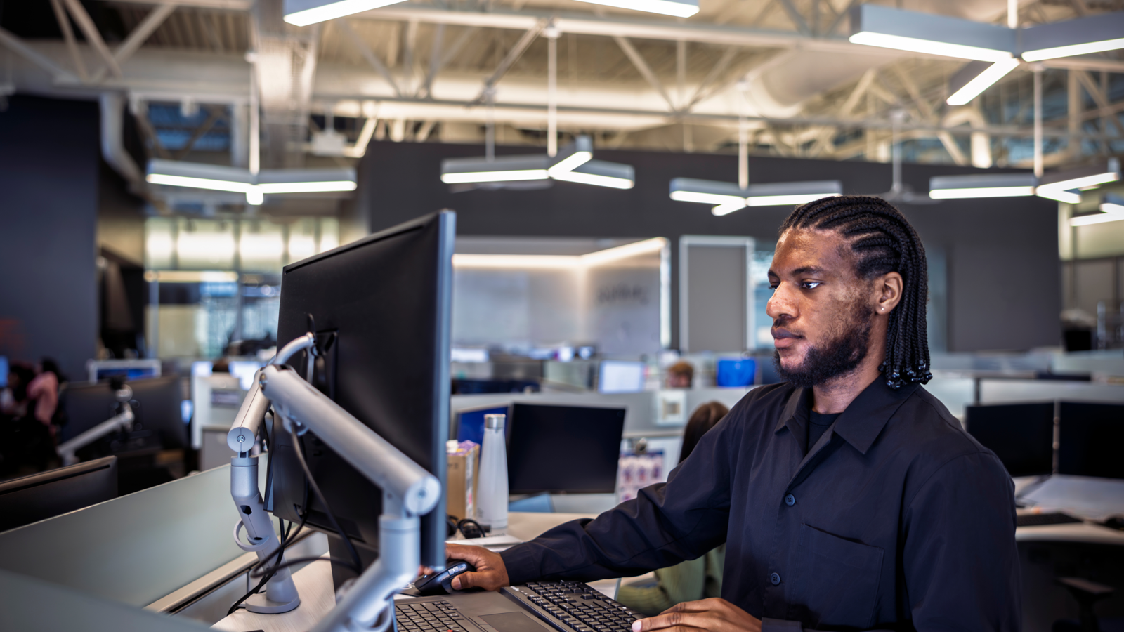 A researcher operates independently in a co working space surrounded by multiple computers leveraging real-time data processing to drive medical technology advancements, precision engineering, and digital health solutions in a high-tech research environment