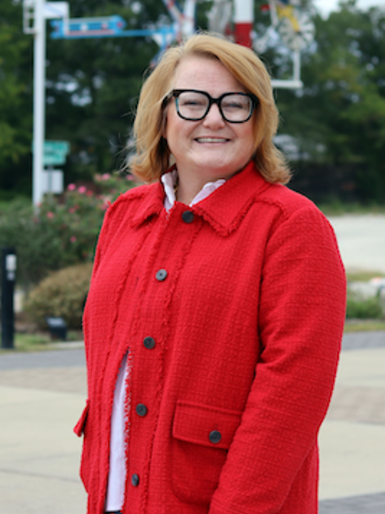 Upper torso portrait of a woman wearing a red jacket standing outside